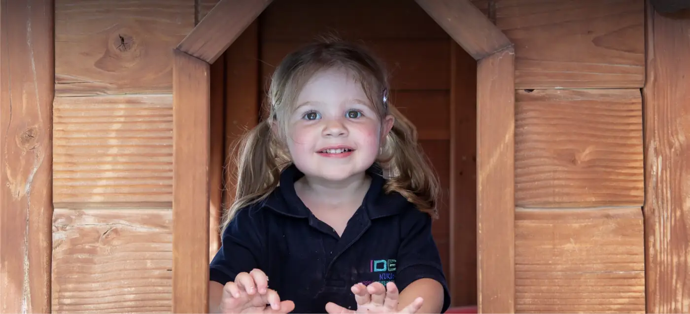 Smiling child in the IDEA ELC outdoor playhouse